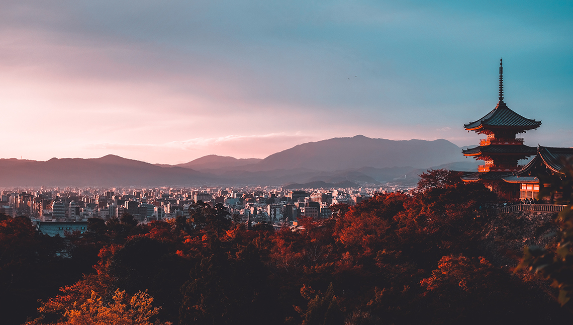 Veduta di Kyoto dall'alto con una pagoda in primo piano e boschi e palazzi sullo sfondo