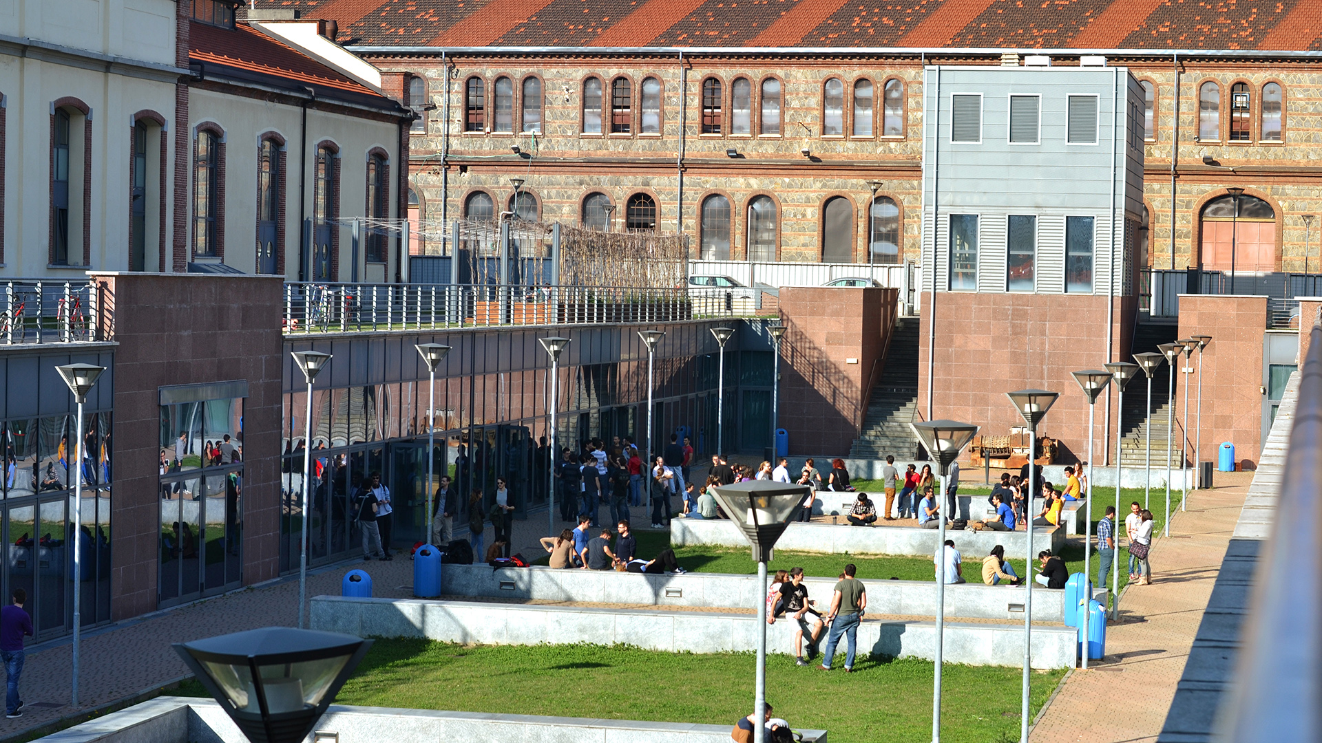 Fotografia della corte interrata del Politecnico di Torino con prato verde e studenti all'aperto