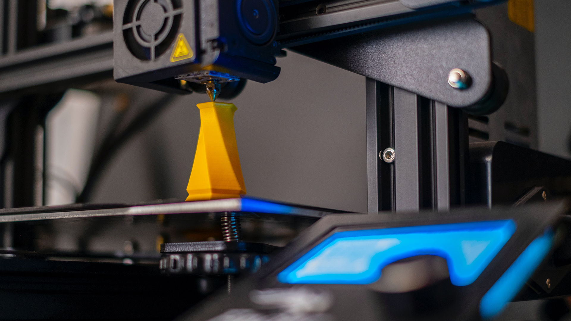 Una stampante 3d al lavoro su un oggetto di colore giallo