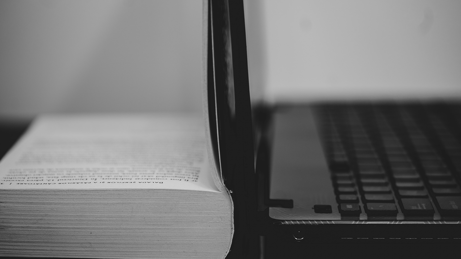 Fotografia in bianco e nero di un libro accanto a un computer