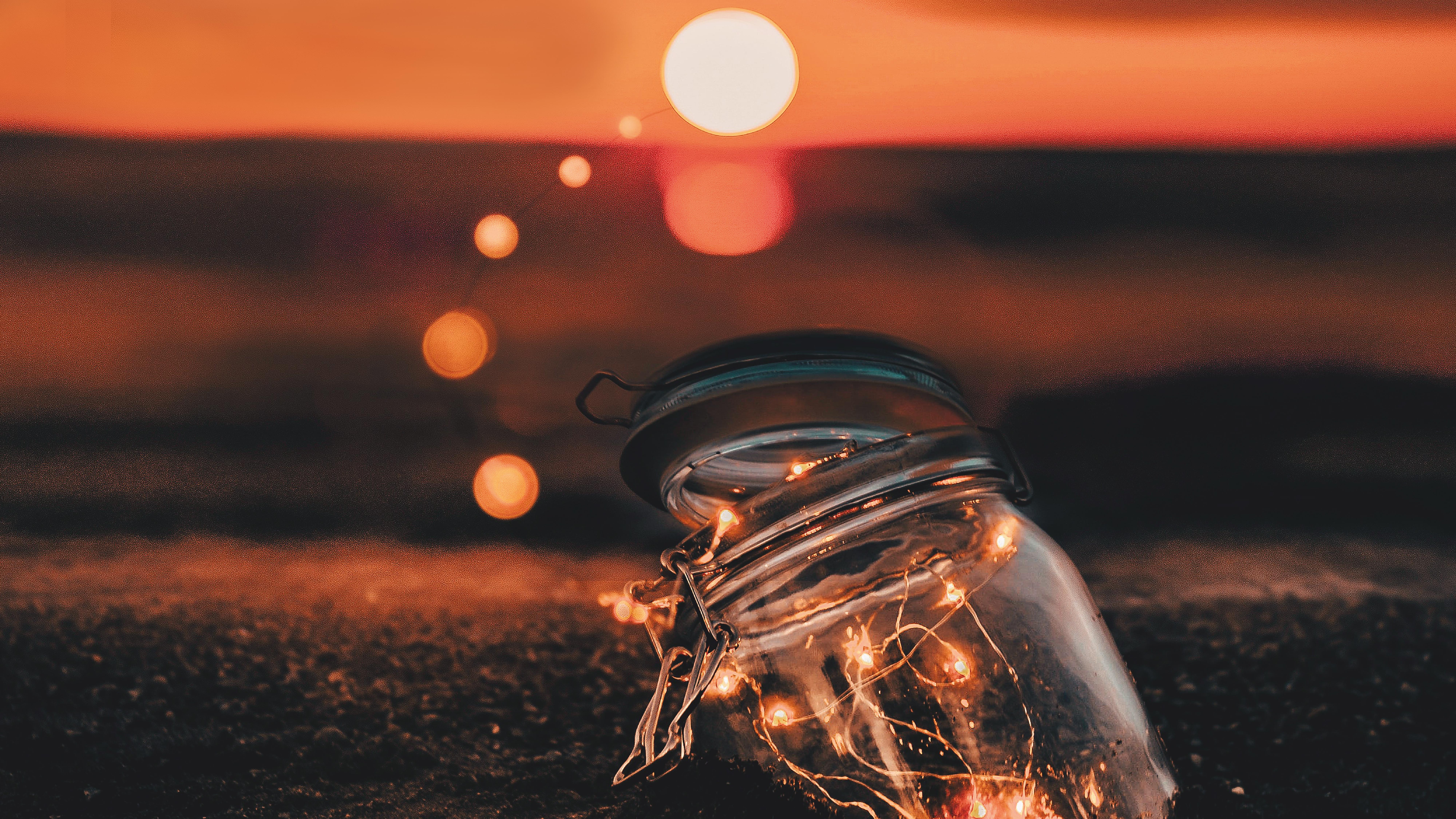 Foto evocativa di un vasetto illuminato sulla spiaggia al tramonto