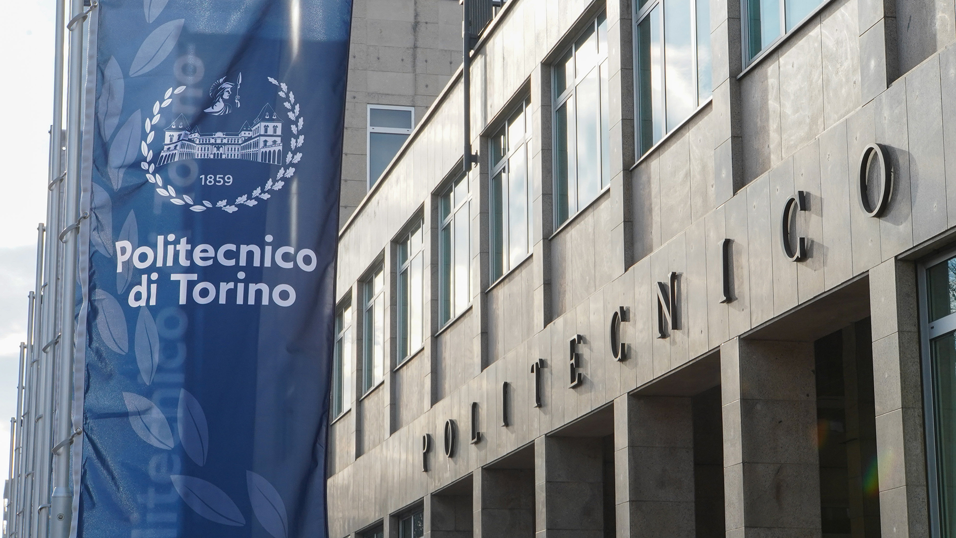 La facciata del Politecnico di Torino con stendardi blu con logo