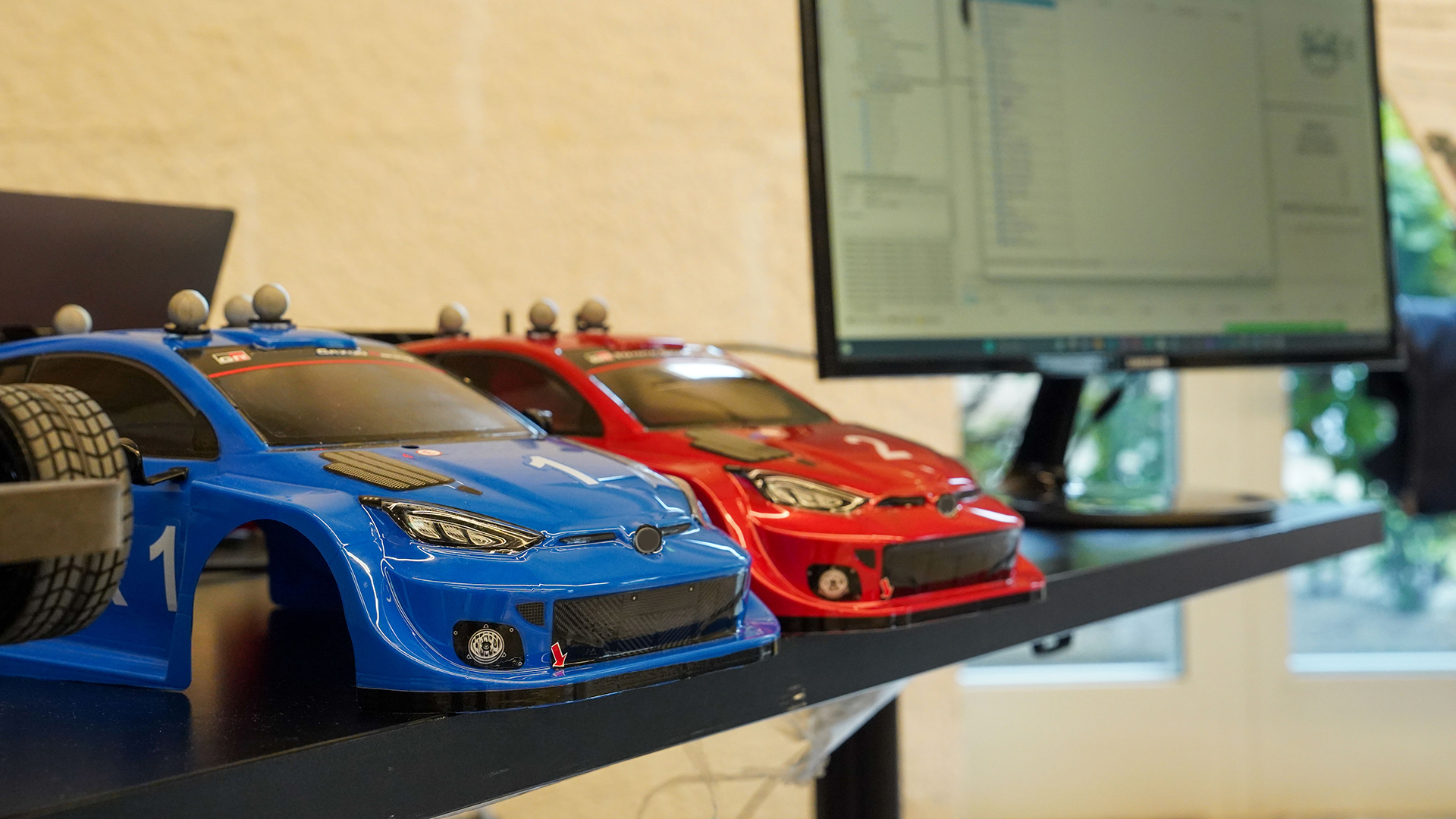 Foto di due modellini di automobile a fianco di un computer