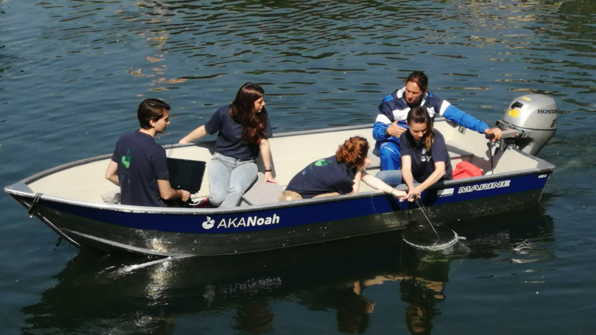 Foto di persone su una barca mentre pescano plastiche in un fiume 