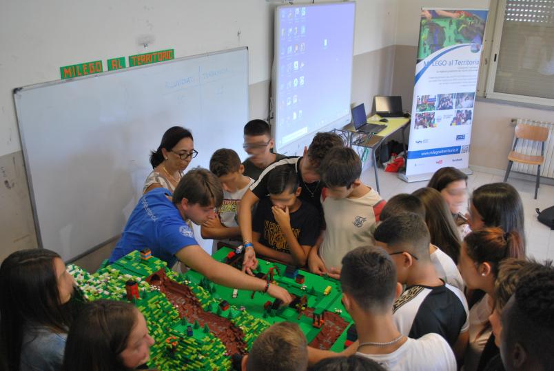 Students of Mi Lego al Territorio team showing a LEGO model to school pupils