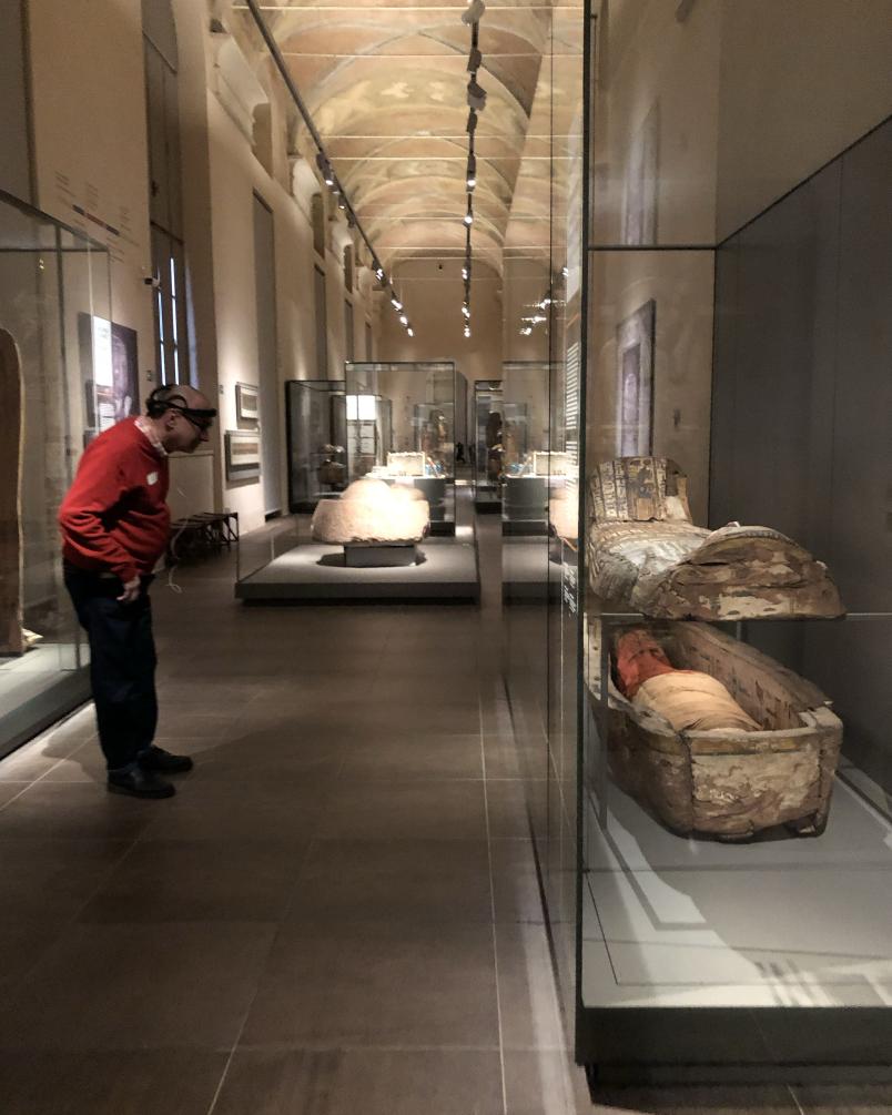 Una persona osserva le mummie nelle teche del Museo Egizio di Torino