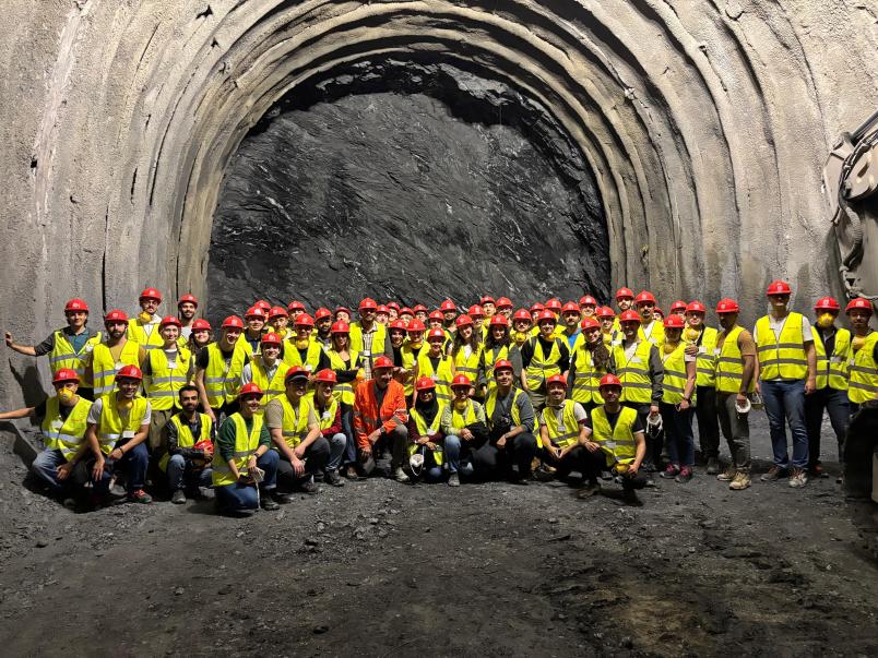 Foto di gruppo di studenti con caschetti e gilet catarifrangenti in una galleria