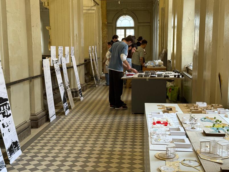 Studenti e studentesse osservano modelli e tavole progettuali durante l’allestimento dell’Exhibition del progetto TNE-DeSK presso l’Università di Belgrado