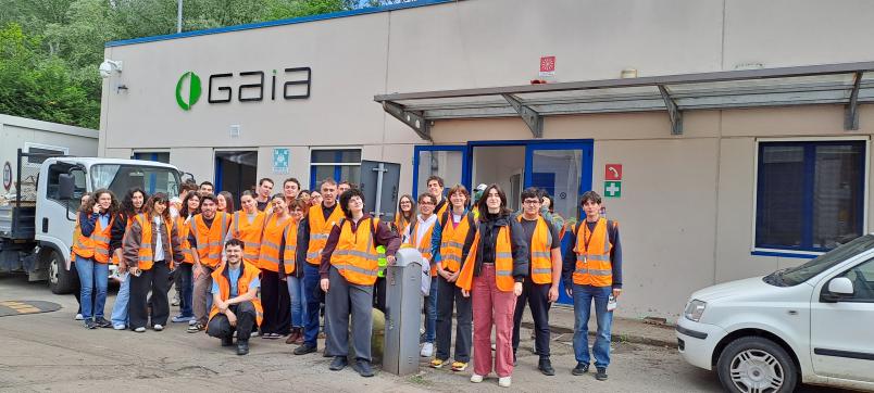 Foto di gruppo di studenti con giacchetti catarifrangenti di fronte all'Impianto di trattamento rifiuti GAIA spa