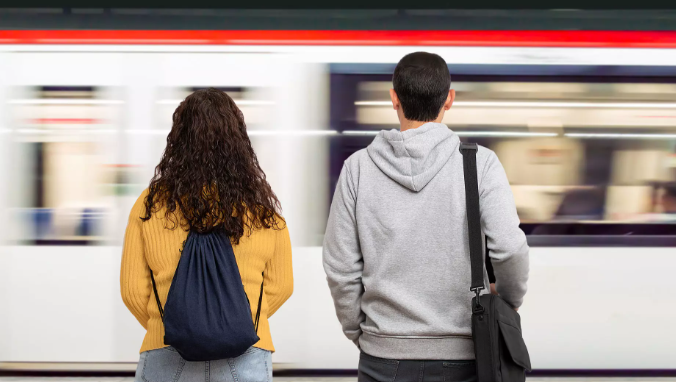 due persone, di spalle che aspettano il treno