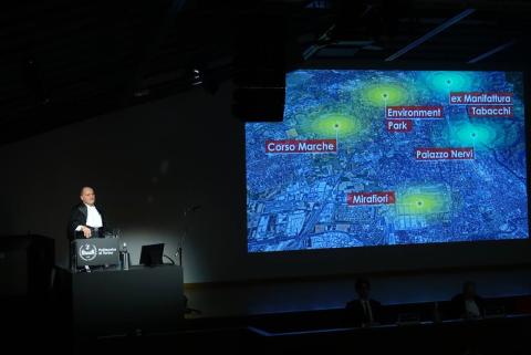 Il rettore presenta la sua relazione dal podio con immagini di Torino sullo schermo