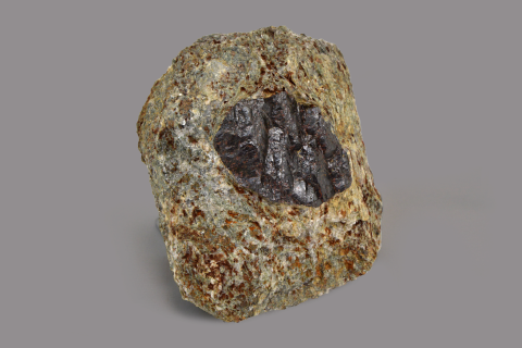 Minerale dalle sfumature marrone chiaro e puntinature rosse con al centro una forma ovale grigio scuro