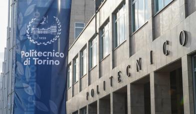 Foto della facciata del Politecnico con uno stendardo blu con logo di Ateneo
