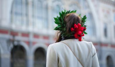 Ragazza girata di spalle con in testa una corona di allora e un fiocco rosso