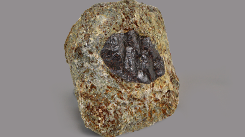Minerale dalle sfumature marrone chiaro e puntinature rosse con al centro una forma ovale grigio scuro